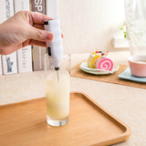 Hand using a digital thermometer to check the temperature of a glass of lemonade on a wooden tray.