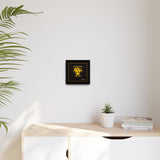 Framed artwork on a wall above a desk with a plant and books.