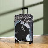 Luggage with a black cat design on a wooden floor against a light green wall