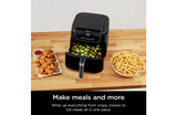 Ninja air fryer on a wooden countertop with various foods around it.