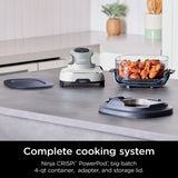 Ninja CRISPI PowerPod cooking system on a kitchen counter with food in a container.