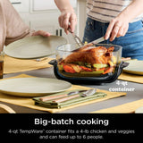 Person carving a roasted chicken in a kitchen with a 4-qt CleanCrisp container.